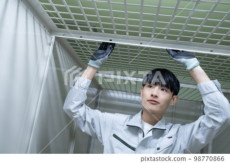 A young man in work clothes who inspects the ceiling to which the net is pasted A young man in work clothes who inspects the ceiling to which the net is pasted 98770866