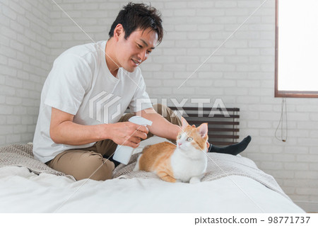 A man spraying a cat (sterilization, discipline, deodorant, odor control, water) 98771737