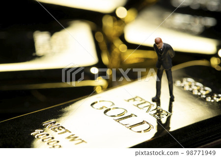 Image of miniature business person and gold nuggets 98771949