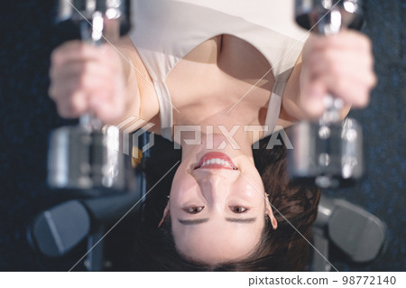 Woman holding dumbbells in both hands at the gym Woman holding dumbbells in both hands at the gym 98772140