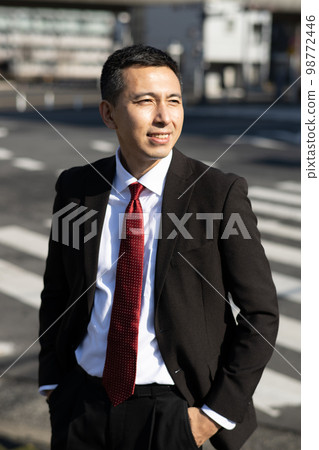 A businessman crossing a pedestrian crossing 98772446