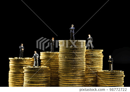 A miniature business person on top of a stack of coins A miniature business person on top of a stack of coins 98772722