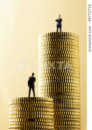 A miniature business person on top of a stack of coins 98772728