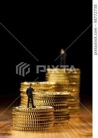 A miniature business person on top of coins stacked in a stepped pattern 98772738