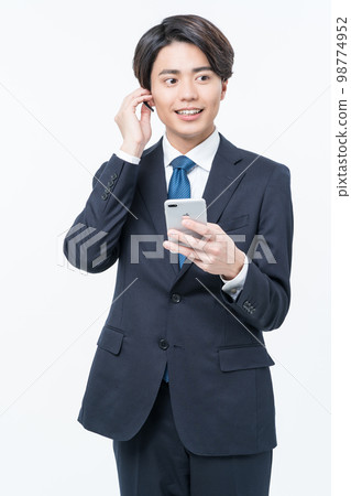 A young man in a suit making a phone call A young man in a suit making a phone call 98774952