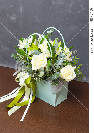 Ash and tea roses in a wicker basket on an old shabby table. Ash and tea roses in a wicker basket on an old shabby table. 98775263