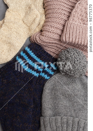 Knitted winter clothes, neatly stacked on a white background. The surface of women's woolen things, textiles. Close-up knitted texture. The background is gray. Casual clothes. 98775370