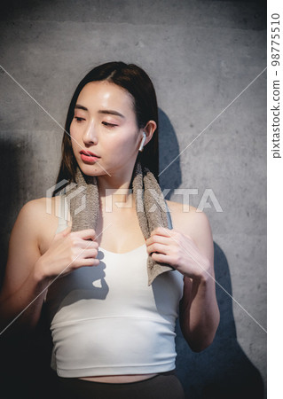 一個女人在健身房裡脖子上掛著毛巾休息 98775510