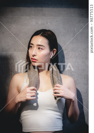 A woman resting with a towel around her neck at the gym A woman resting with a towel around her neck at the gym 98775513