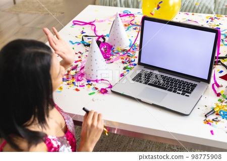 Image of biracial woman using laptop with copy space on screen having party at home 98775908