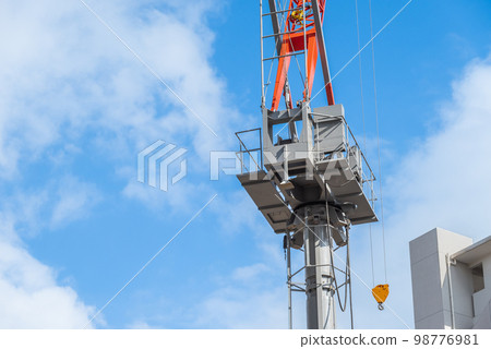 Cranes at a construction site under a blue sky 98776981