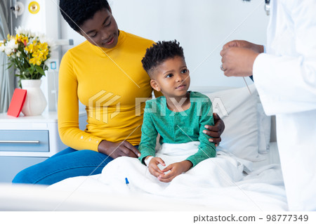 Smiling african american son patient with mother and male doctor in hospital 98777349