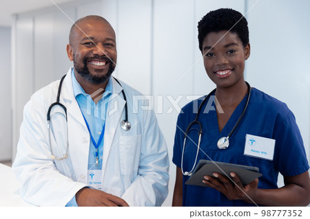 Portrait of smiling african american male and female doctor in hospital corridor 98777352