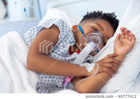 African american boy patient on ventilator asleep in hospital bed 98777422