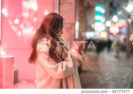 Woman looking at mobile phone in night city Woman looking at mobile phone in night city 98777477