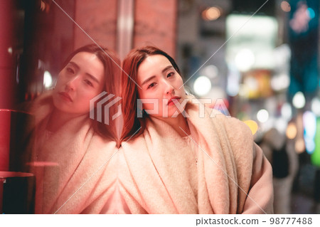 Woman leaning against shop window Woman leaning against shop window 98777488