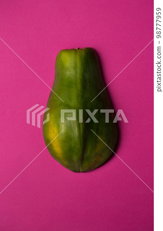 Half of a papaya lies skin side up on a bright background Half of a papaya lies skin side up on a bright background 98777959
