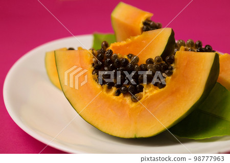 Fresh juicy papaya in a plate on a pink Viva Magenta color background Fresh juicy papaya in a plate on a pink Viva Magenta color background 98777963