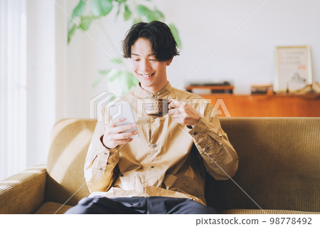 Man looking at smartphone while drinking coffee 98778492