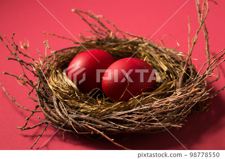 Big red eggs in a nest on a pink background Big red eggs in a nest on a pink background 98778550