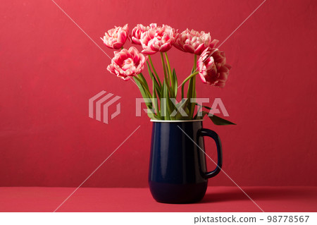 Beautiful spring bouquet of pink tulips in a blue decanter on a pink background Beautiful spring bouquet of pink tulips in a blue decanter on a pink background 98778567