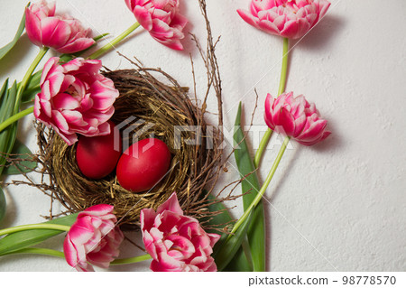 A nest with painted eggs is decorated with beautiful pink tulips A nest with painted eggs is decorated with beautiful pink tulips 98778570