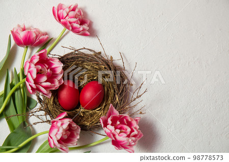 A nest with eggs is decorated with beautiful pink tulips A nest with eggs is decorated with beautiful pink tulips 98778573