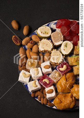 A large plate of oriental sweets and nuts on a dark background 98778584