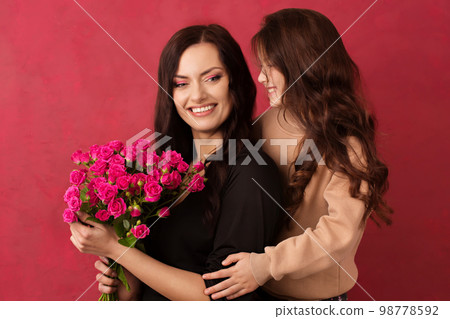 The girl greets her mother with a beautiful bouquet of pink roses on a Viva Magenta color background 98778592