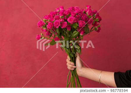 bouquet of pink roses in female hands on a pink background bouquet of pink roses in female hands on a pink background 98778594