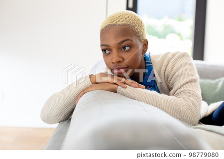 Happy african american woman sitting on sofa in living room 98779080