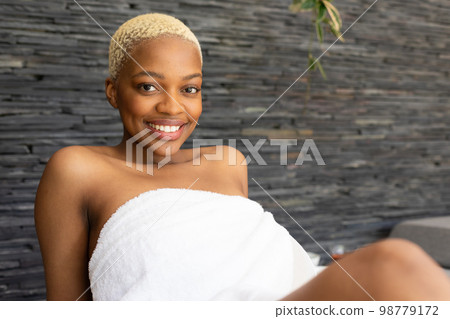 Portrait of happy african american woman wearing towel, looking at camera and smiling Portrait of happy african american woman wearing towel, looking at camera and smiling 98779172