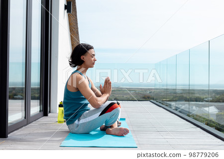 Happy biracial man doing yoga, meditating on balcony Happy biracial man doing yoga, meditating on balcony 98779206