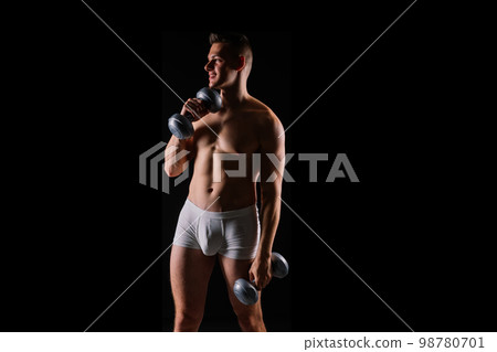 Shirtless bodybuilder holding dumbell and showing his muscular arms. 98780701