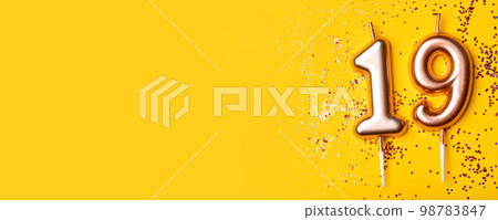 Gold candles in the form of number nineteen on yellow background with confetti. 19 years celebration. Greeting banner. Gold candles in the form of number nineteen on yellow background with confetti. 19 years celebration. Greeting banner. 98783847