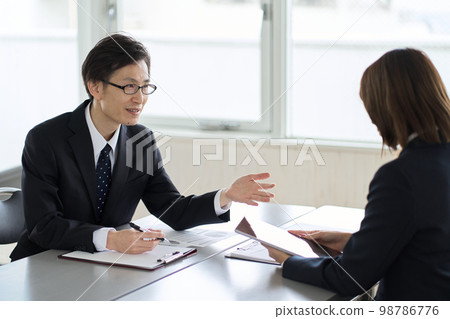 Asian business person showing and explaining a tablet Asian business person showing and explaining a tablet 98786776