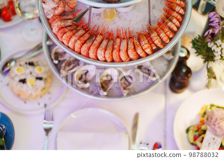 shrimp and shells with oysters on a platter with ice, lemons and sauce.  98788032