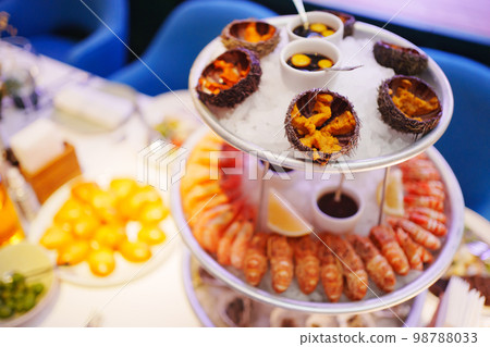 sea urchins, shrimp and shells with oysters on a platter with ice. 98788033