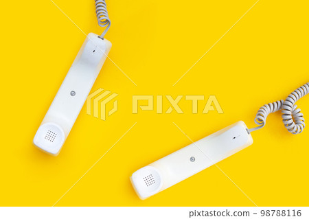 Handset of landline phones on yellow background. 98788116