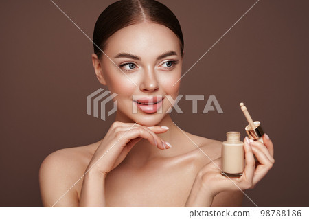 Portrait beautiful young woman with foundation bottle Portrait beautiful young woman with foundation bottle 98788186