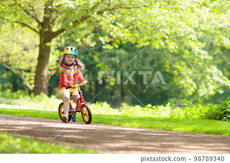 Kids ride balance bike in park Kids ride balance bike in park 98789340
