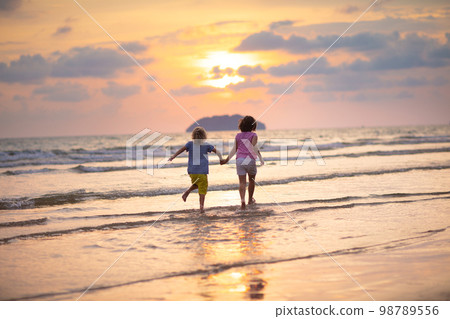 Child playing on ocean beach. Kid at sunset sea. 98789556