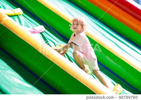 Child jumping on playground trampoline. Kids jump. 98789760