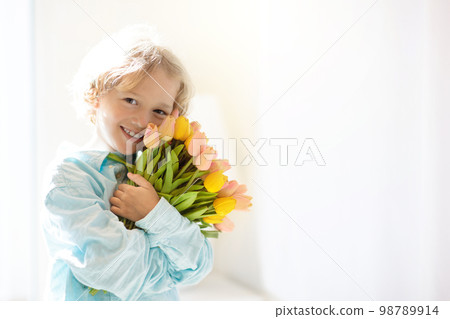 Child with flower bouquet. Mother day greeting. 98789914