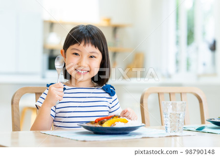 Elementary school girl eating curry Elementary school girl eating curry 98790148