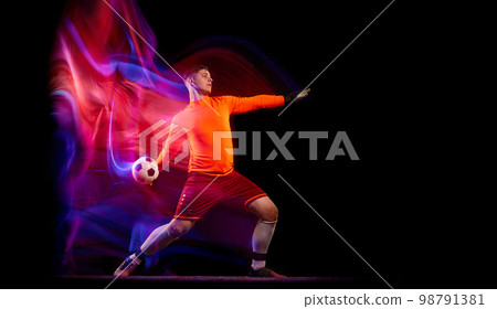 Sportive energetic man, soccer football goalkeeper in action, motion over dark background with mixed neon light. Concept of sport, achievement, competition, goals. Sportive energetic man, soccer football goalkeeper in action, motion over dark background with mixed neon light. Concept of sport, achievement, competition, goals. 98791381