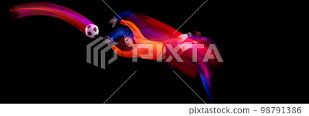 Sportive energetic man, soccer football goalkeeper in action, motion over dark background with mixed neon light. Concept of sport, achievement, competition, goals. Sportive energetic man, soccer football goalkeeper in action, motion over dark background with mixed neon light. Concept of sport, achievement, competition, goals. 98791386
