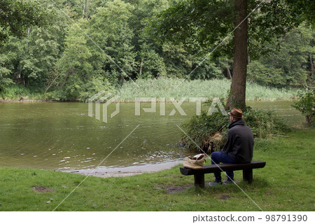Relax on a lakeside bench. The green color of nature has a calming and soothing effect. 98791390