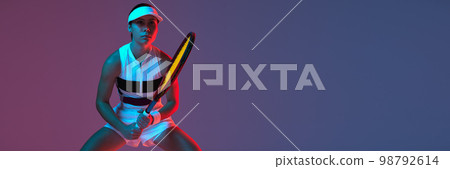 Portrait of young professional female tennis player in sports uniform in motion, action over gradient pink-purple background in neon light. Sport, fashion, energy, motivation concept Portrait of young professional female tennis player in sports uniform in motion, action over gradient pink-purple background in neon light. Sport, fashion, energy, motivation concept 98792614