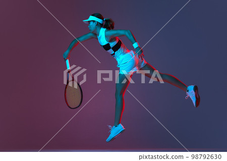 Back view of professional tennis player playing tennis over pink-purple background in neon light. Concept of sport, health, strength, action, motion, lifestyle. 98792630